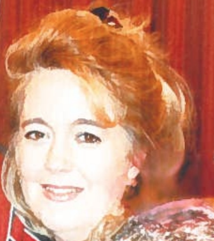 A woman with red hair smiles, with a blurred background of red and brown.
