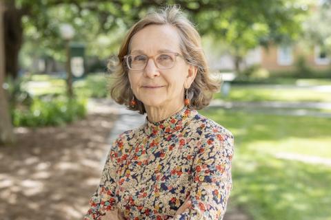 Woman with glasses and floral shirt outdoors.