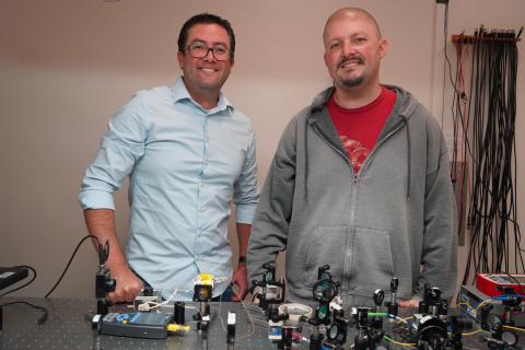Two men standing behind a table with scientific equipment.