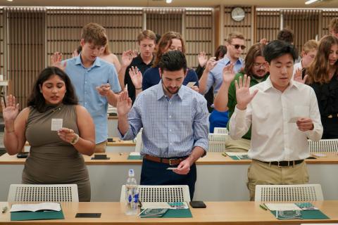 Group of people with hands raised, taking an oath.