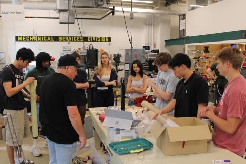 Group of students and an instructor working on a project in a workshop.