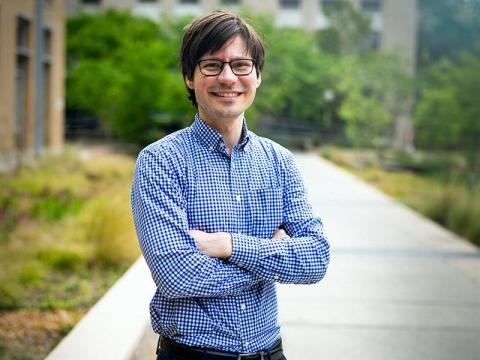 Man with glasses in a blue checkered shirt with arms crossed.