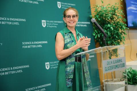 Woman in green dress applauds at a podium.