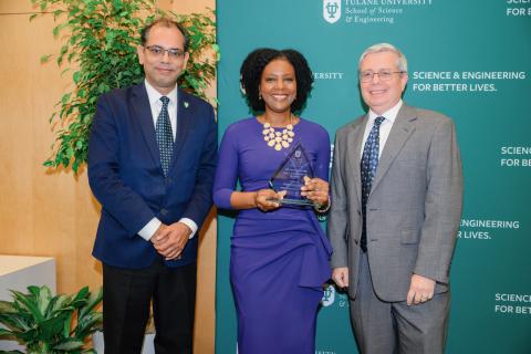 Three people pose for a photo, two men and one woman holding an award.