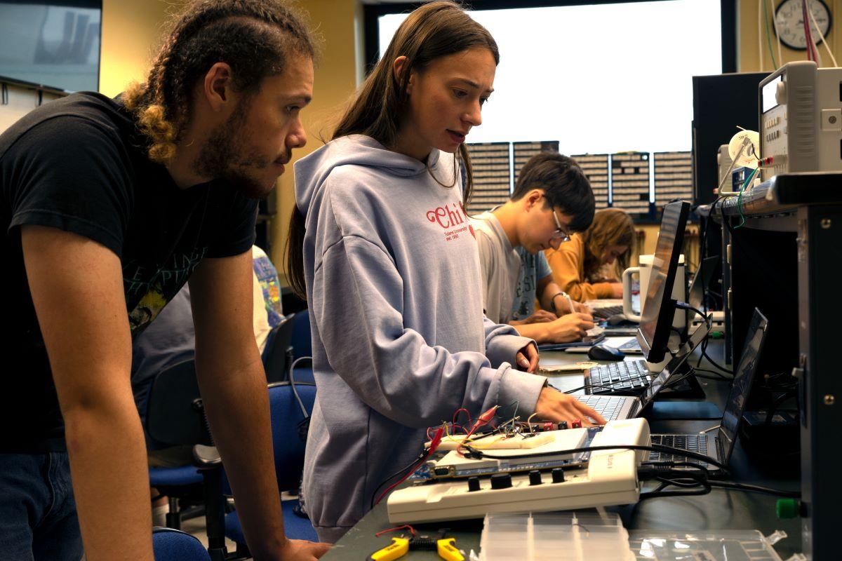 Students building a circuit to measure electrical activity in muscles in the undergraduate electronics lab.