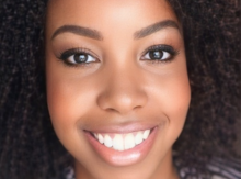 Close-up photograph of a smiling woman with curly hair.