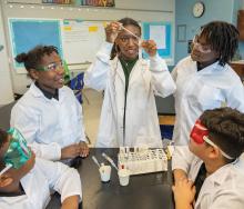 Students in lab coats conduct a science experiment.