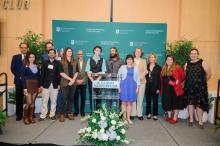 A group of twelve people pose for a photo behind a podium decorated with flowers.